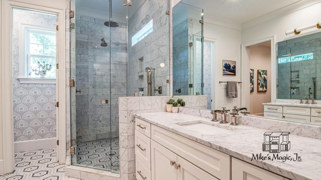 Remodeled bathroom with a white custom vanity, marble countertop, and frameless glass walk-in shower