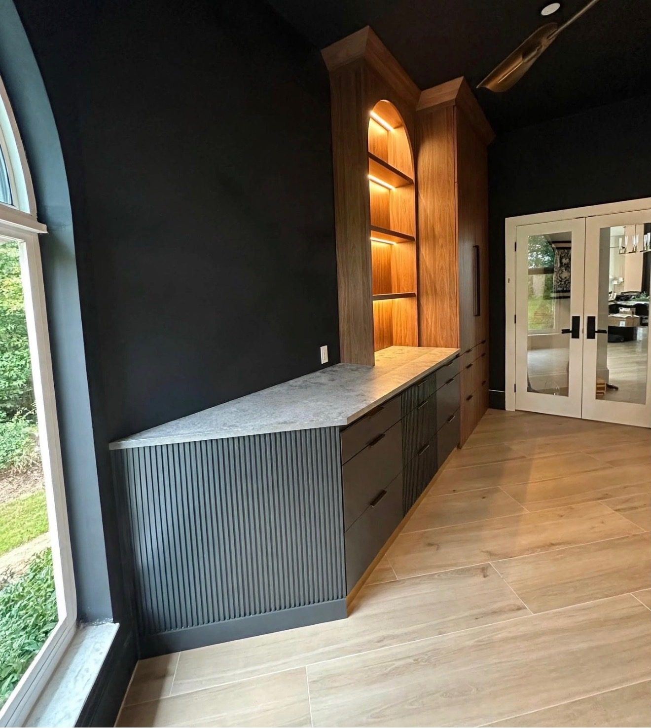 Designer office with dark fluted cabinetry and lighted shelves