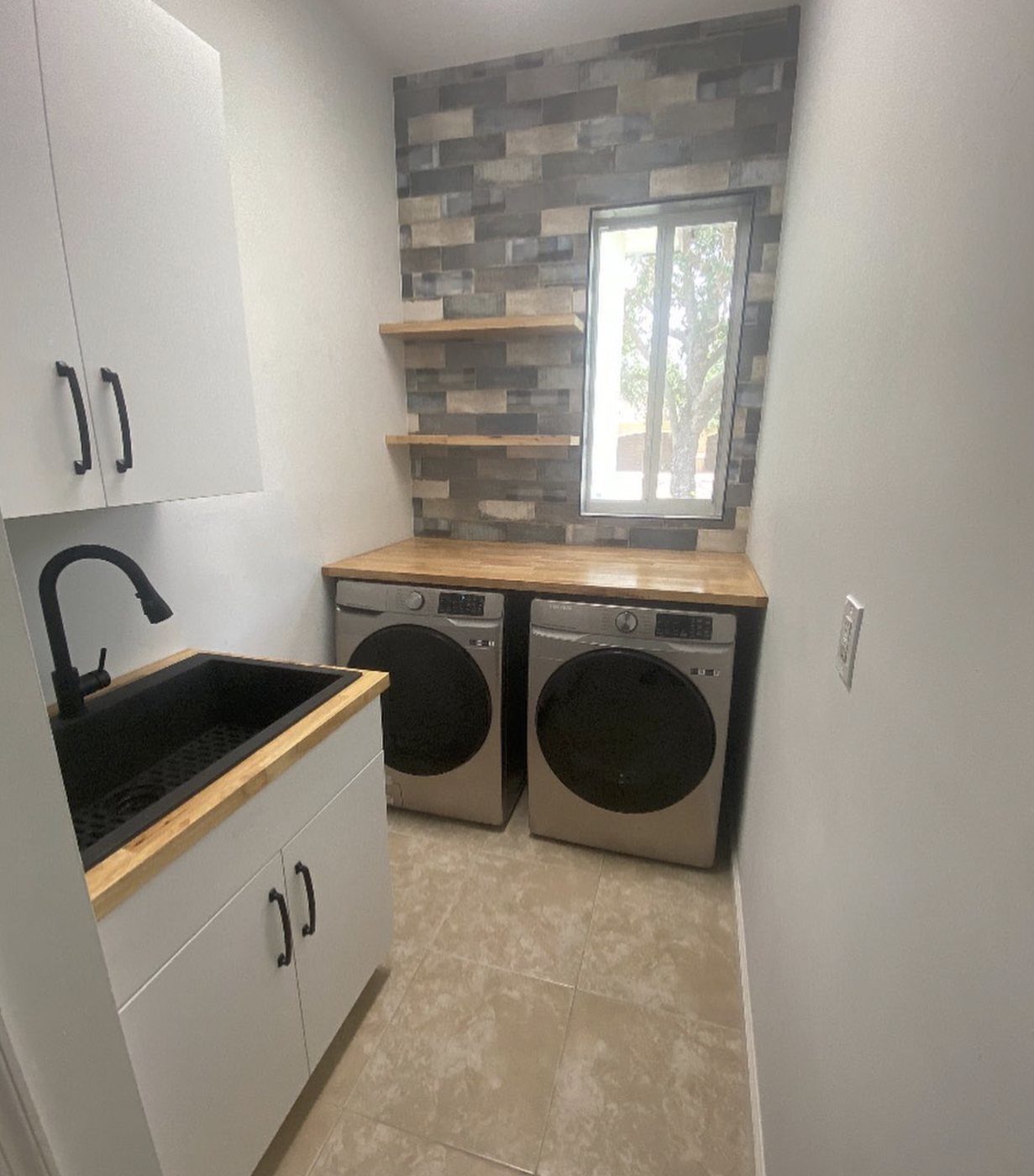 Custom laundry room with white cabinets, utility sink, and wood counter