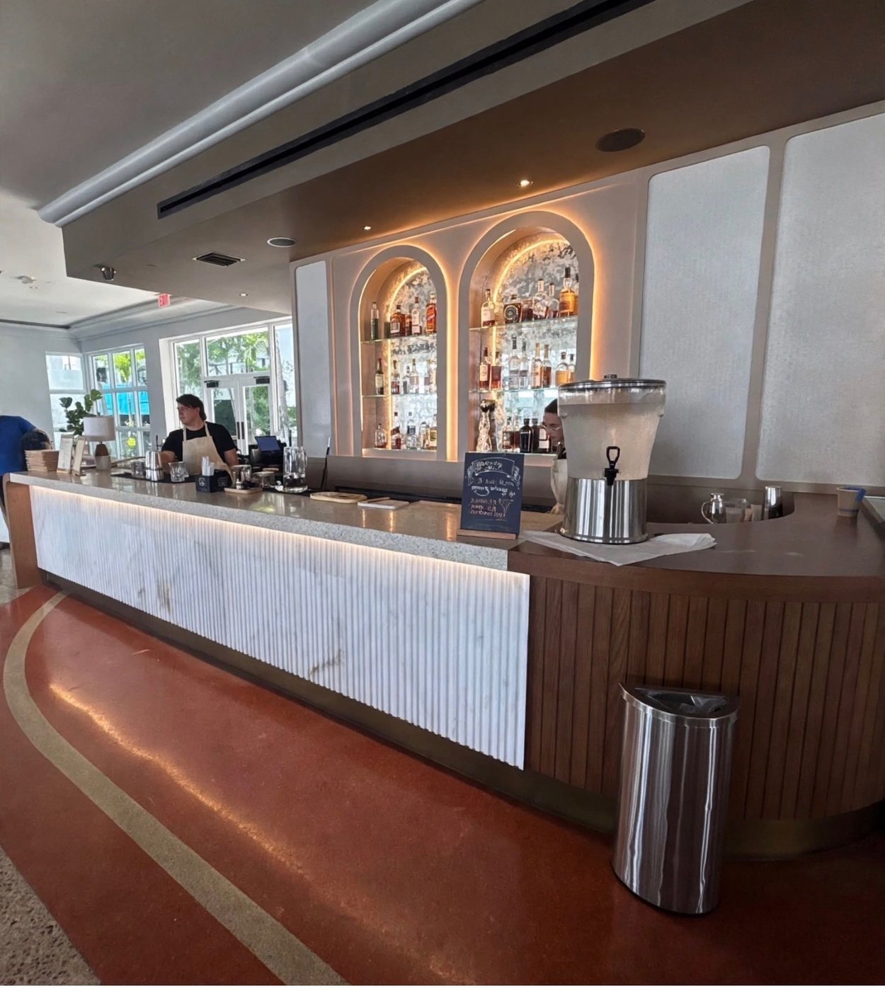 Commercial bar with custom fluted front and arched lighted shelving